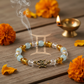 Dhan Yog Gemini Bracelet in a serene spiritual setting with diya and marigolds