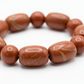 Red jasper bracelet macro detail showing natural earthy brick-red colour and smooth texture of individual beads