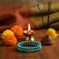 Turquoise Bracelet with blue-green stones in a spiritual Indian setting with diya, marigold flowers and incense