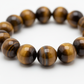 Tiger Eye Bracelet close-up of golden brown chatoyant tiger eye beads on white background